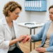 Консультация ревматолога: врач осматривает отёчные суставы кистей пациентки с артритом